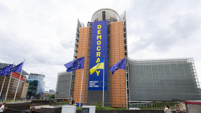 Bâtiment de la Commission européenne à Bruxelles avec des drapeaux européens.