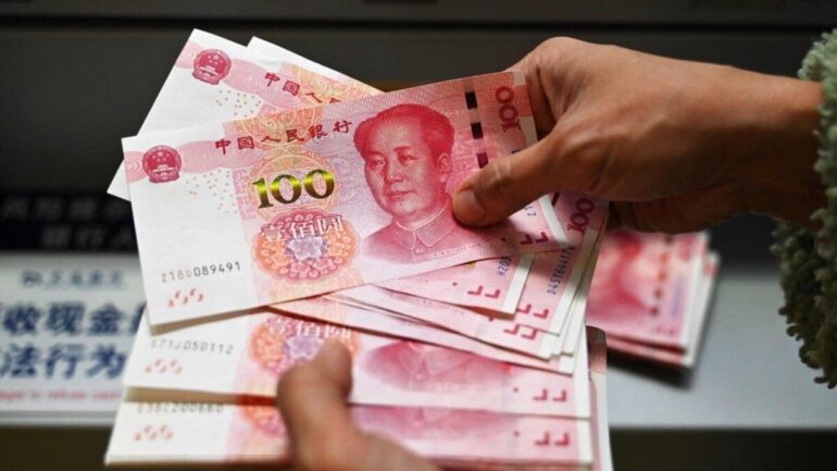 des billets de cent yuans sont comptés dans une agence bancaire en Chine.